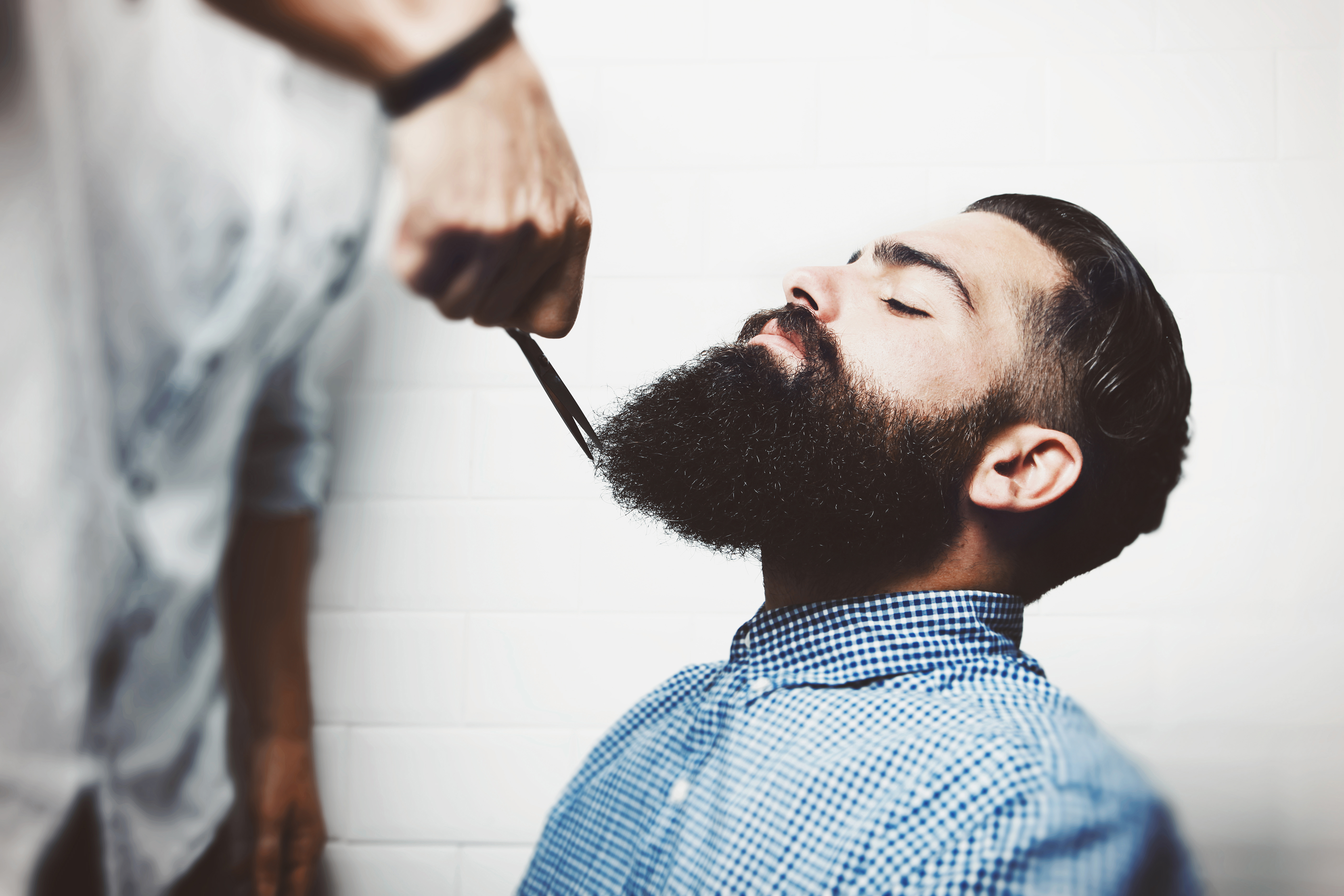 Мужчина бреет бороду. Стрижка бороды. Мужские прически в барбершопе. Стильная борода. Мужская борода.